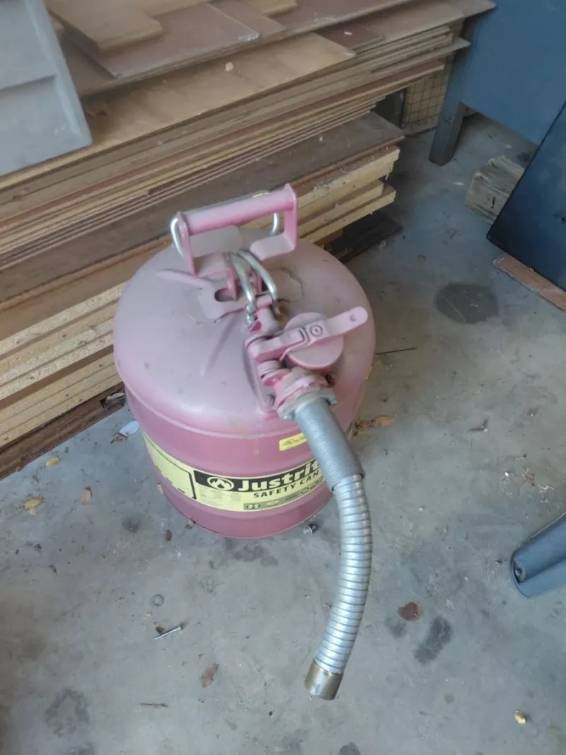 Red Justrite metal safety gas can with flexible hose spout