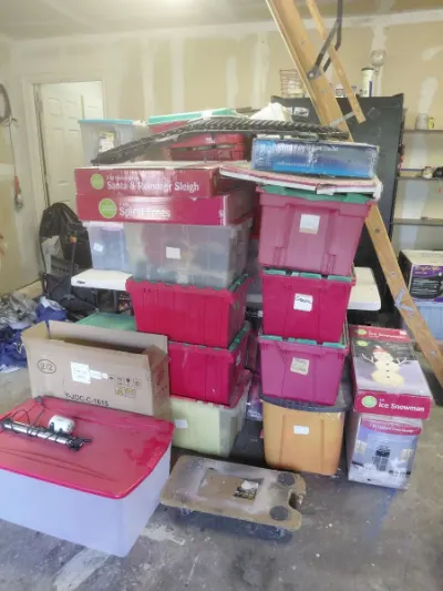 Stacked red Christmas storage totes with Santa sleigh, spiral trees and ice snowman decor boxes