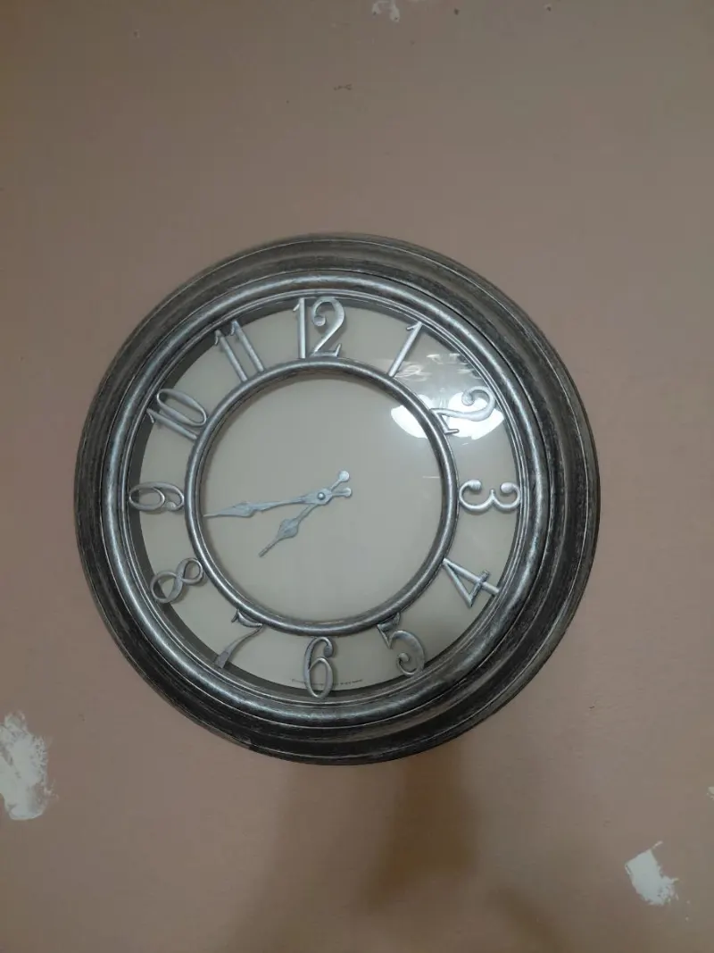 Round silver-tone wall clock with raised Arabic numerals and cream face