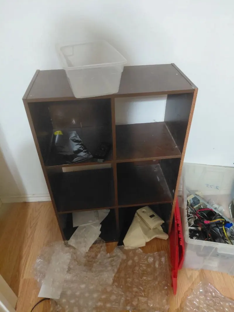 Dark brown 6-cube storage bookcase with plastic bins and computer cables