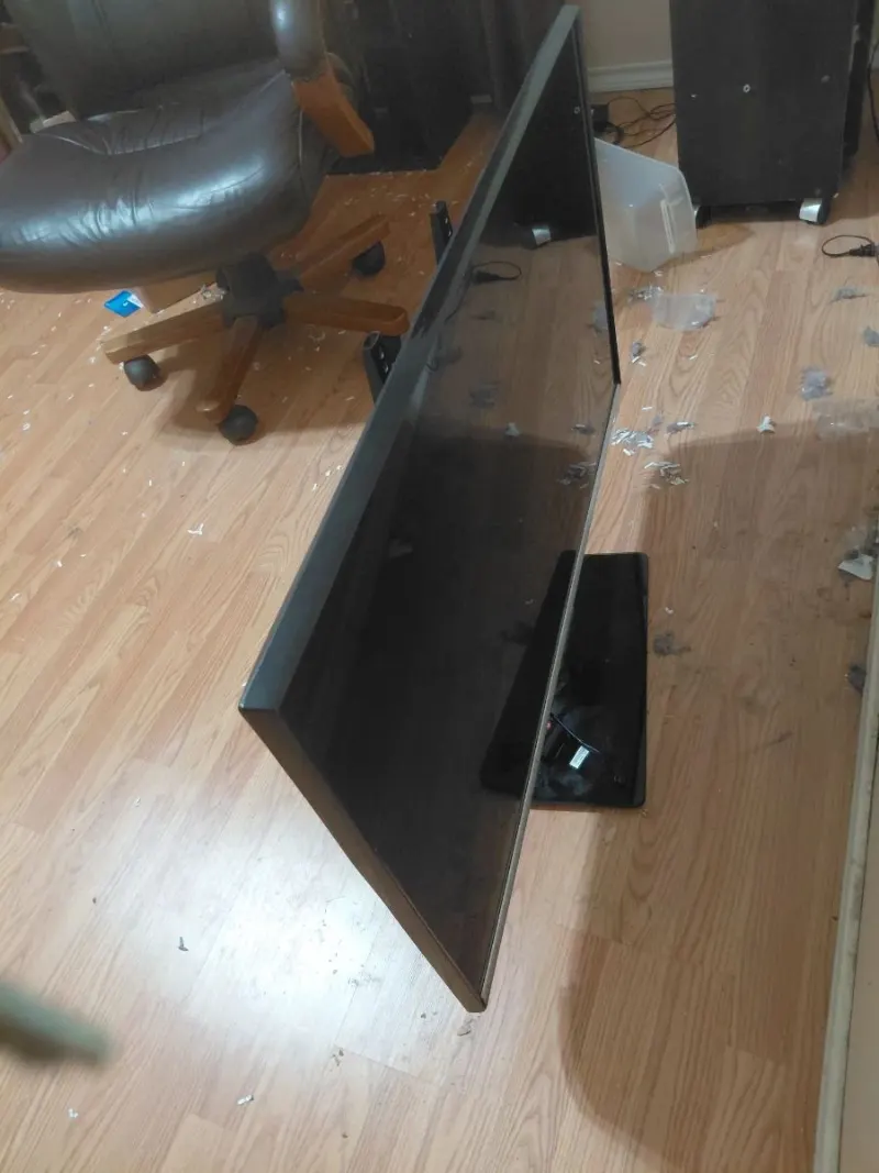 Black flat screen TV on stand with leather office chair on wood floor