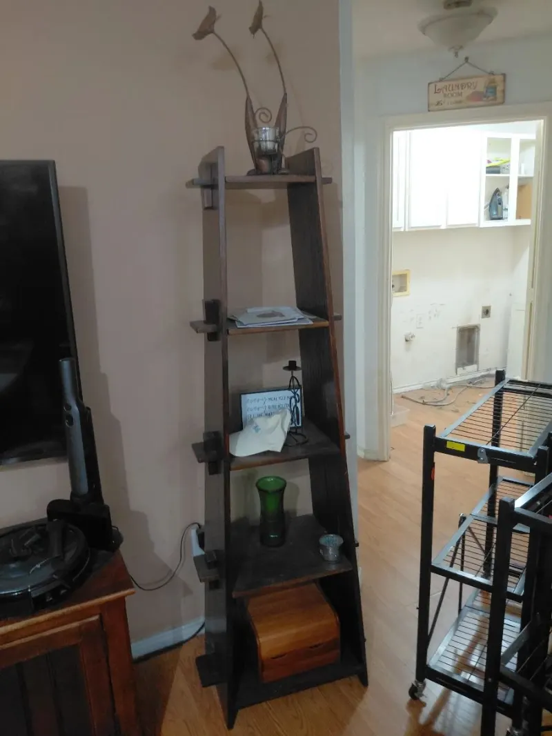 Dark wood A-frame ladder bookshelf with decor, wooden box and metal rolling carts