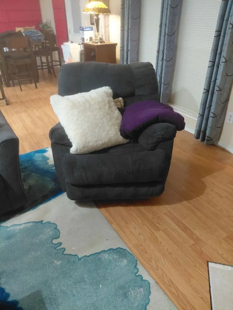 Charcoal gray upholstered recliner chair with white faux fur pillow